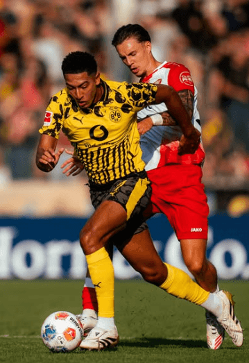 Borussia Dortmund player in yellow-black jersey dribbles past a siegen defender during a pre- season friendly foot ball match